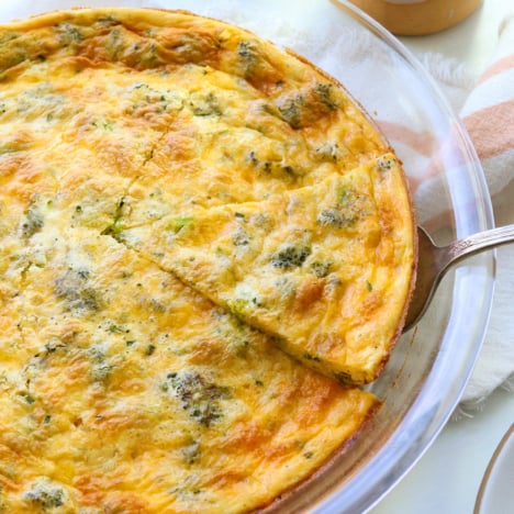 crustless quiche slice lifted out of a glass pie dish.